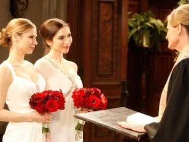 Lesbisk brudepar i hvide ens hvide brudekjoler og brudebuket af røde blomster
